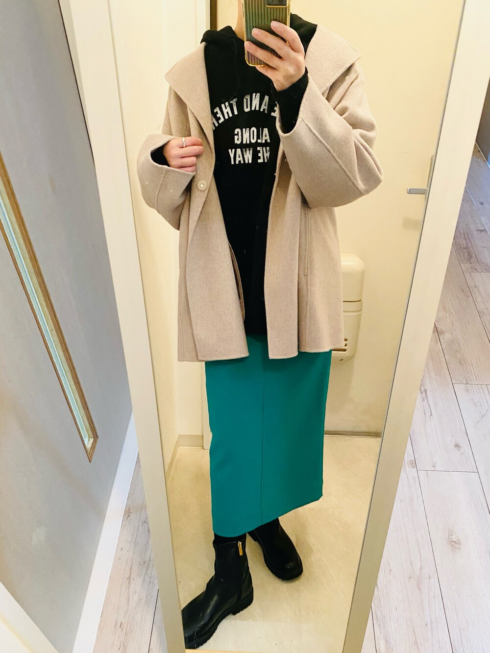 ブラック系のパーカー、グリーン系のスカート、ブラック系のブーツを着用したレディースの冬コーディネートの2枚目の写真