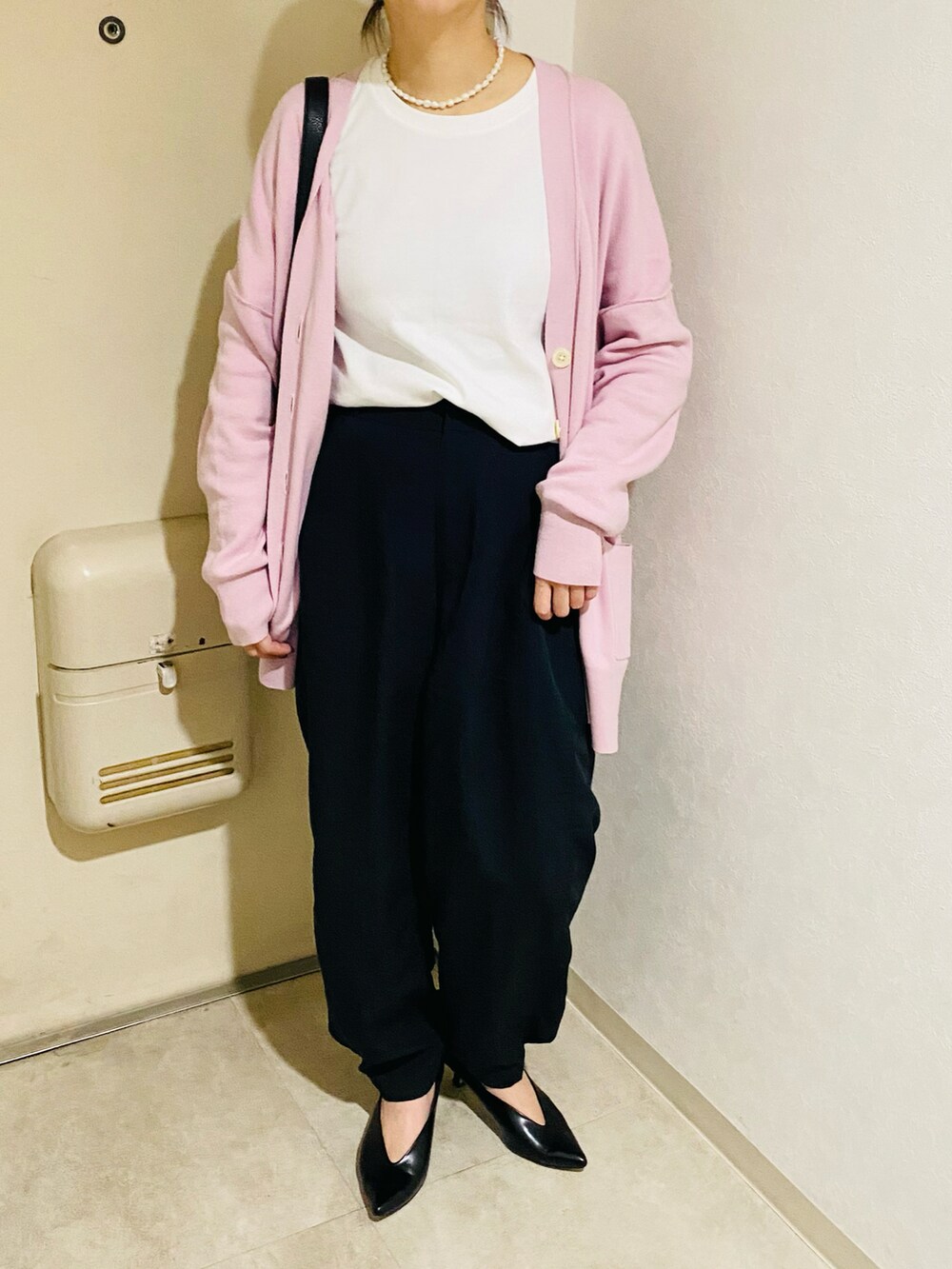 ピンク系のカーディガン/ボレロ、ブラック系のパンプス、ブラック系のパンツを着用したレディースの秋コーディネートの2枚目の写真