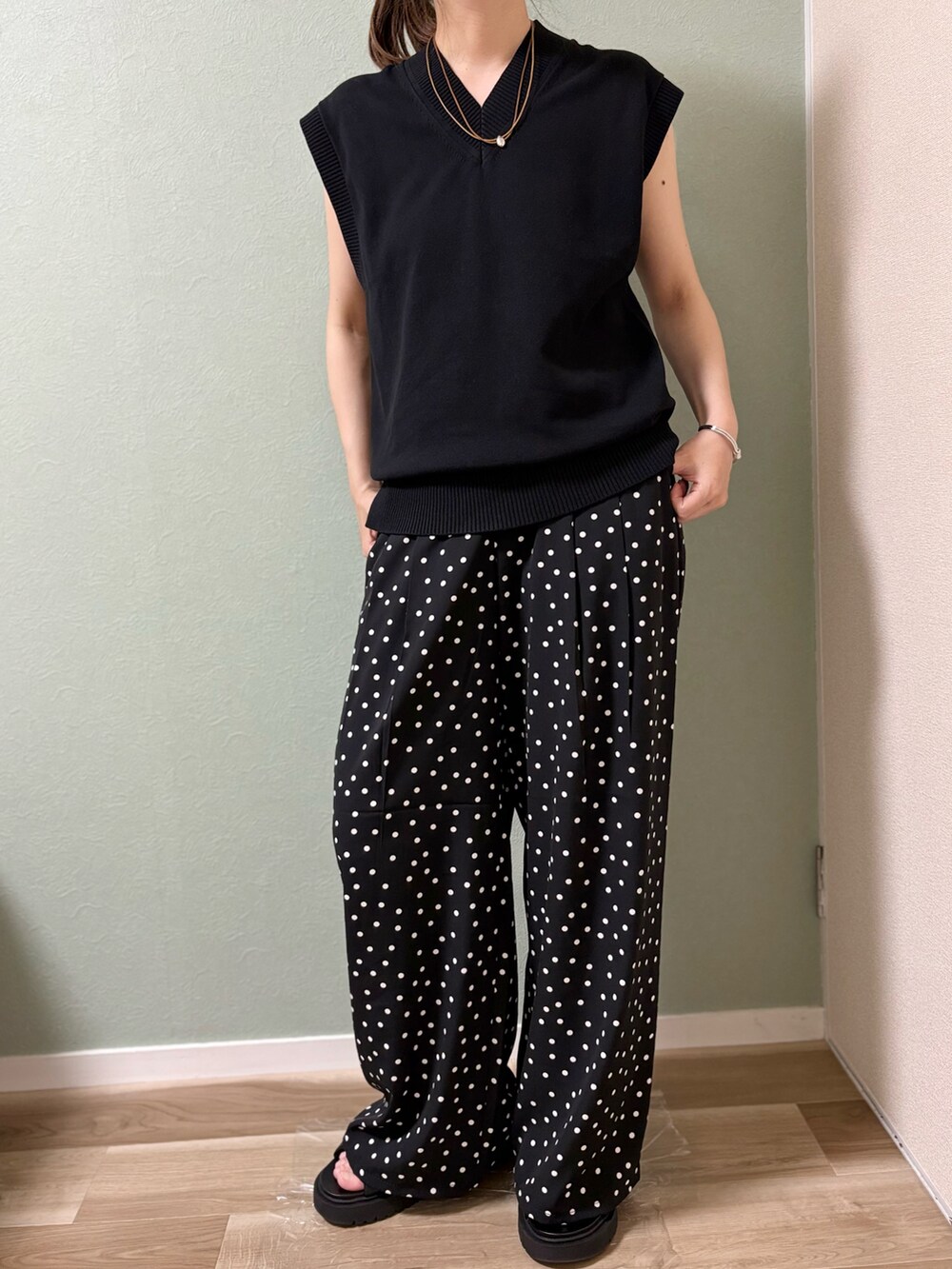 ブラック系のパンツ、ブラック系のベスト、ブラック系のサンダルを着用したレディースの夏コーディネートの2枚目の写真