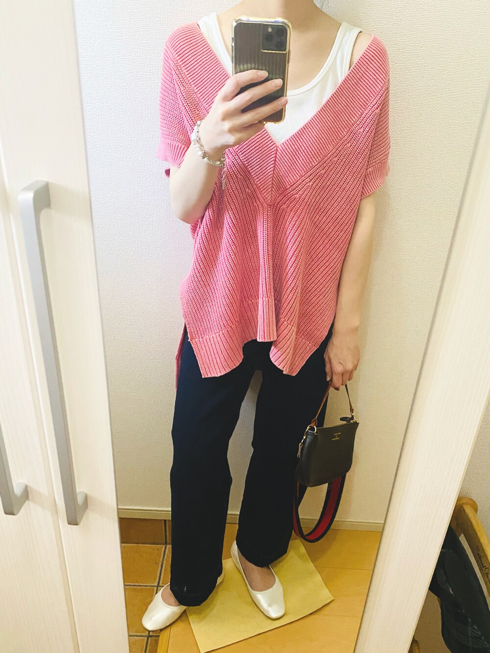 ピンク系のベスト、ホワイト系のタンクトップ、ブルー系のデニムパンツを着用したレディースの春コーディネートの2枚目の写真