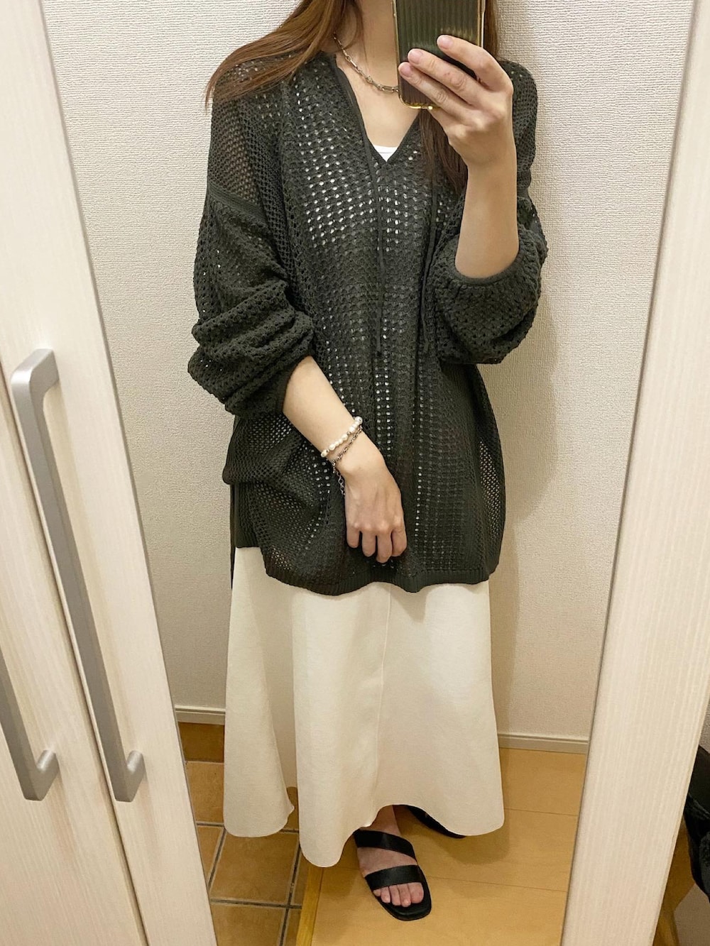グリーン系のニット/セーター、ホワイト系のスカート、ブラック系のサンダルを着用したレディースの春コーディネートの2枚目の写真
