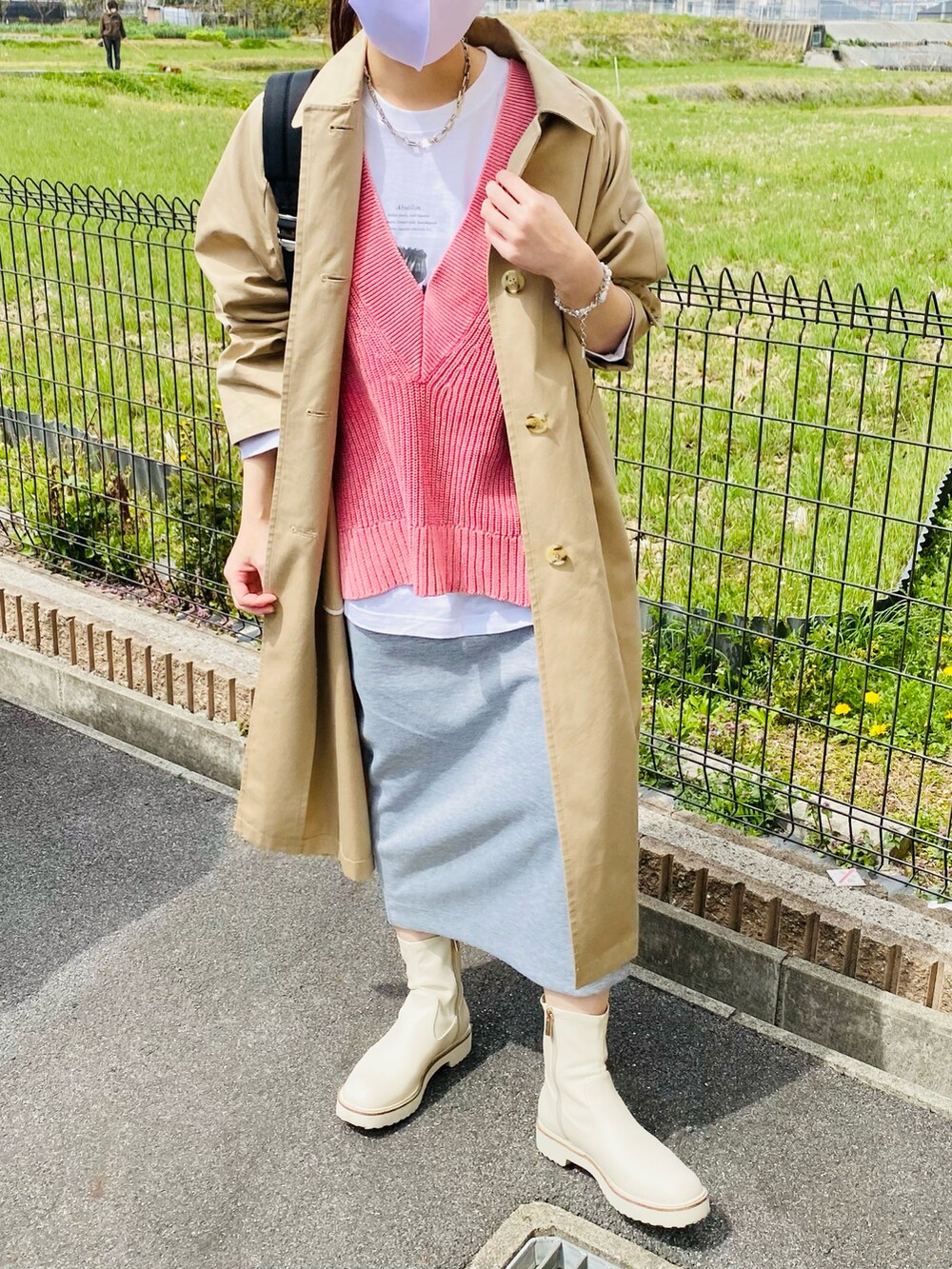 ピンク系のベスト、ホワイト系のTシャツ/カットソー、ベージュ系のステンカラーコートを着用したレディースの春コーディネートの3枚目の写真