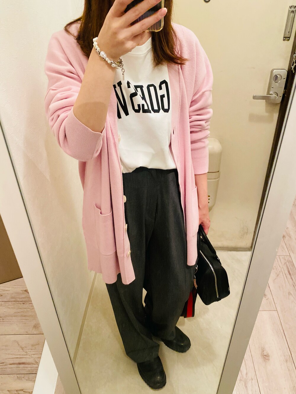 ピンク系のカーディガン/ボレロ、ホワイト系のTシャツ/カットソー、ブラック系のブーツを着用したレディースの秋コーディネートの2枚目の写真