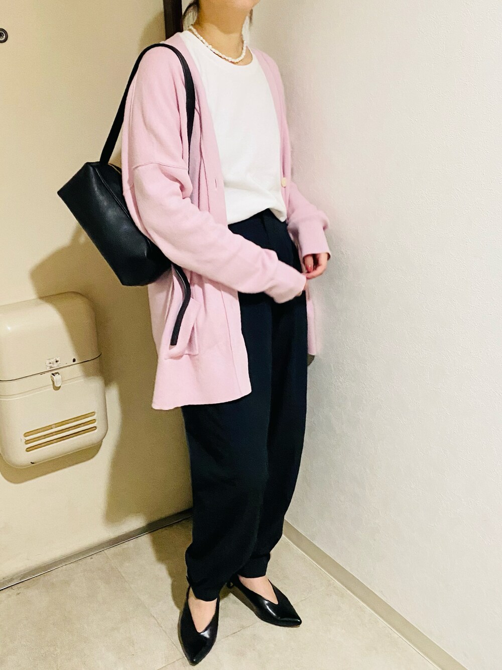 ピンク系のカーディガン/ボレロ、ブラック系のパンプス、ブラック系のパンツを着用したレディースの秋コーディネートの3枚目の写真
