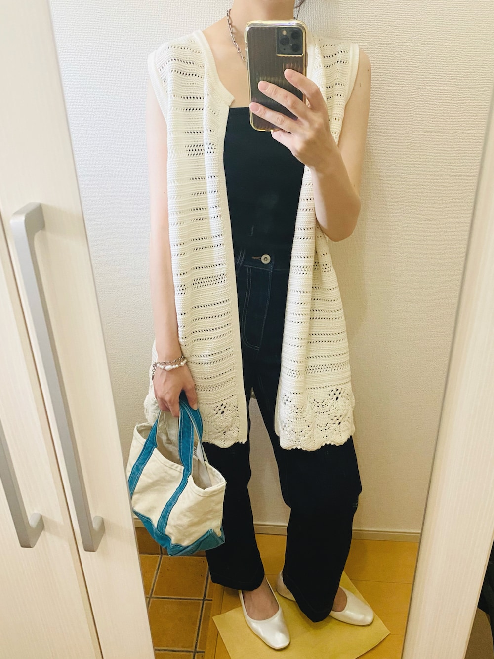 ブラック系のタンクトップ、ブルー系のデニムパンツ、ホワイト系のベストを着用したレディースの春コーディネートの3枚目の写真