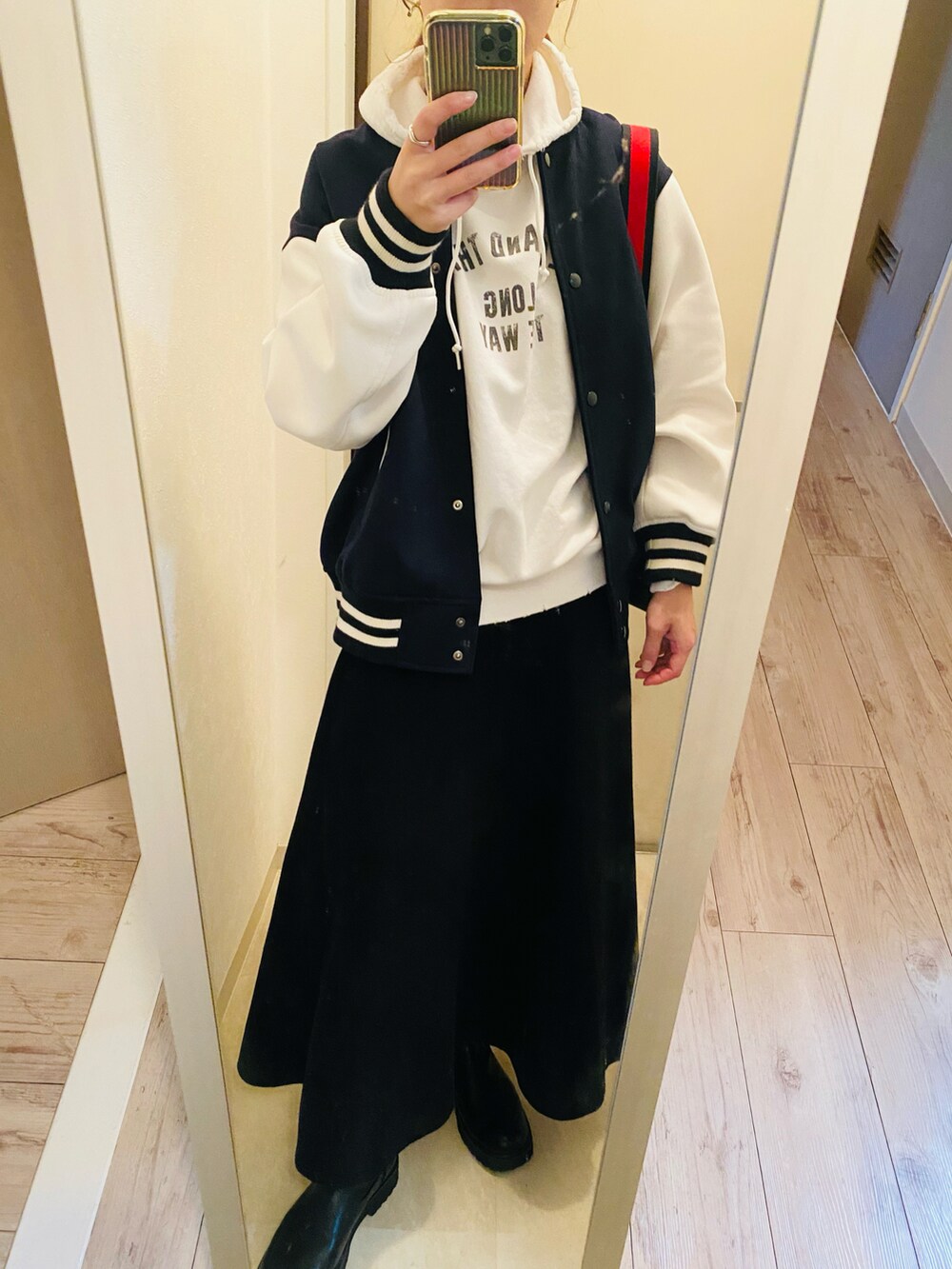 ブラック系のショルダーバッグ、ブラック系のスカート、ホワイト系のパーカーを着用したレディースの秋コーディネートの2枚目の写真