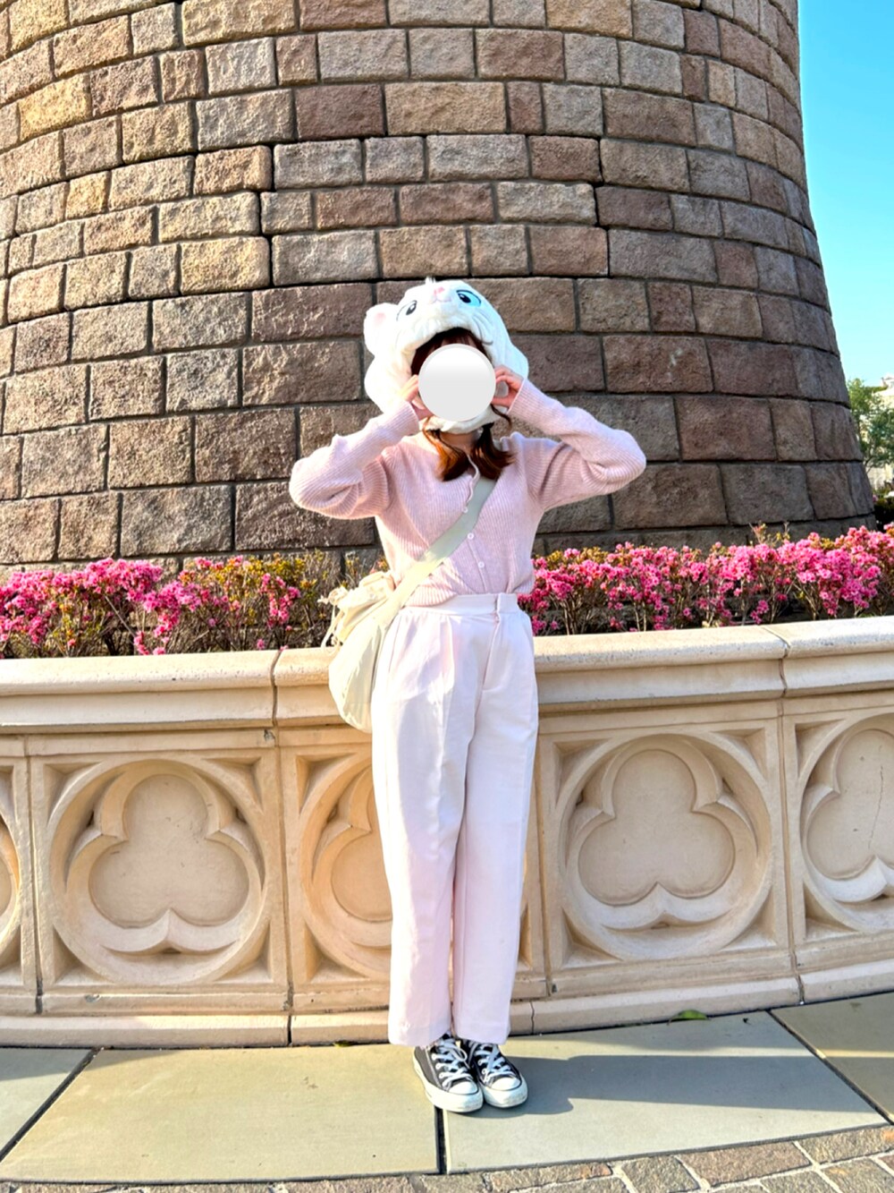 ピンク系のニット/セーター、ベージュ系のショルダーバッグ、ピンク系のスラックスを着用したレディースの春コーディネートの2枚目の写真