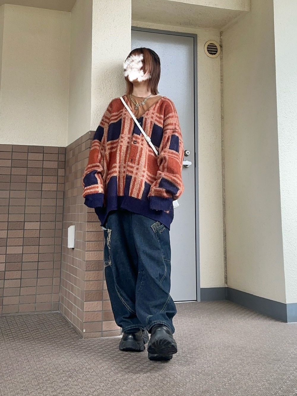 ブルー系のデニムパンツ、ホワイト系のショルダーバッグ、ブラック系のブーツを着用したレディースの春コーディネートの2枚目の写真