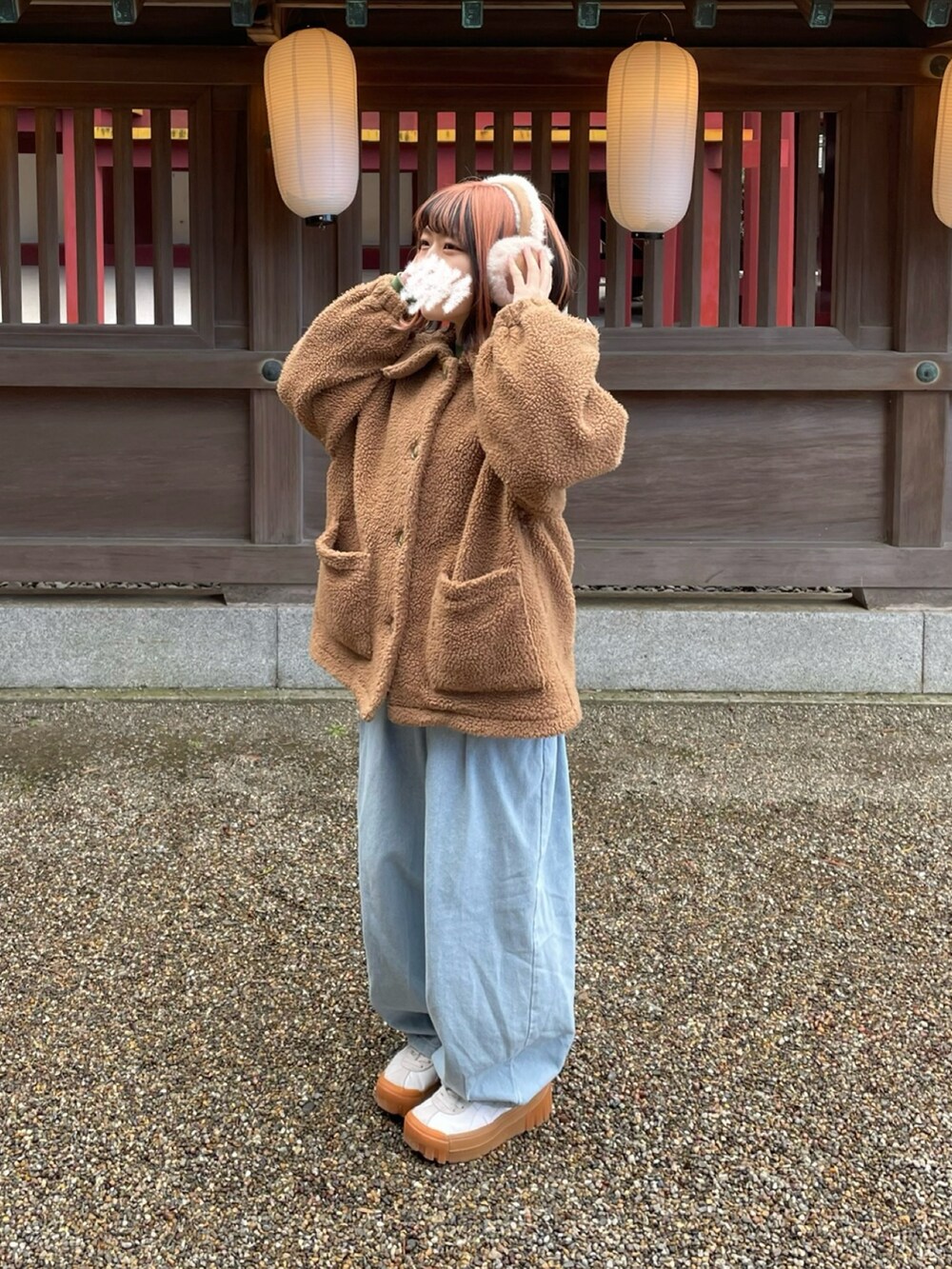 ブラウン系のジャケット/アウター、ブルー系のデニムパンツ、ホワイト系のスニーカーを着用したレディースの冬コーディネートの2枚目の写真