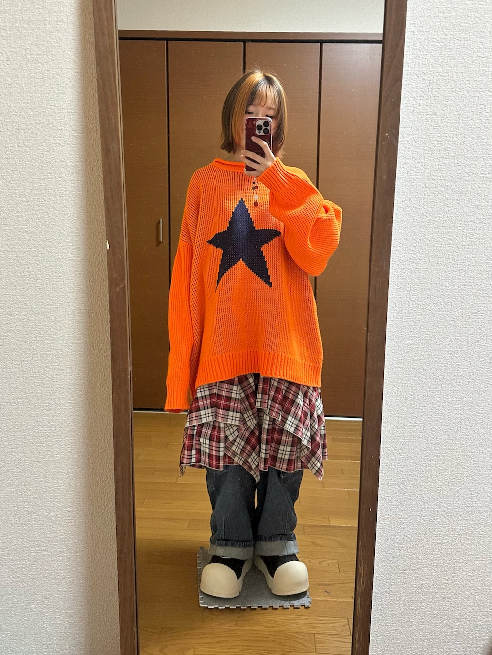 ブラック系のブーツ、オレンジ系のニット/セーター、ブルー系のデニムパンツを着用したレディースの冬コーディネートの2枚目の写真