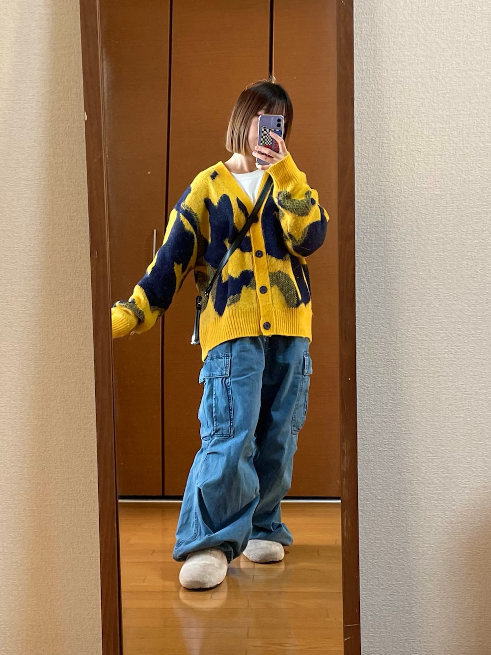 ブルー系のカーゴパンツ、イエロー系のカーディガン/ボレロ、ブラック系のショルダーバッグを着用したレディースの冬コーディネートの2枚目の写真