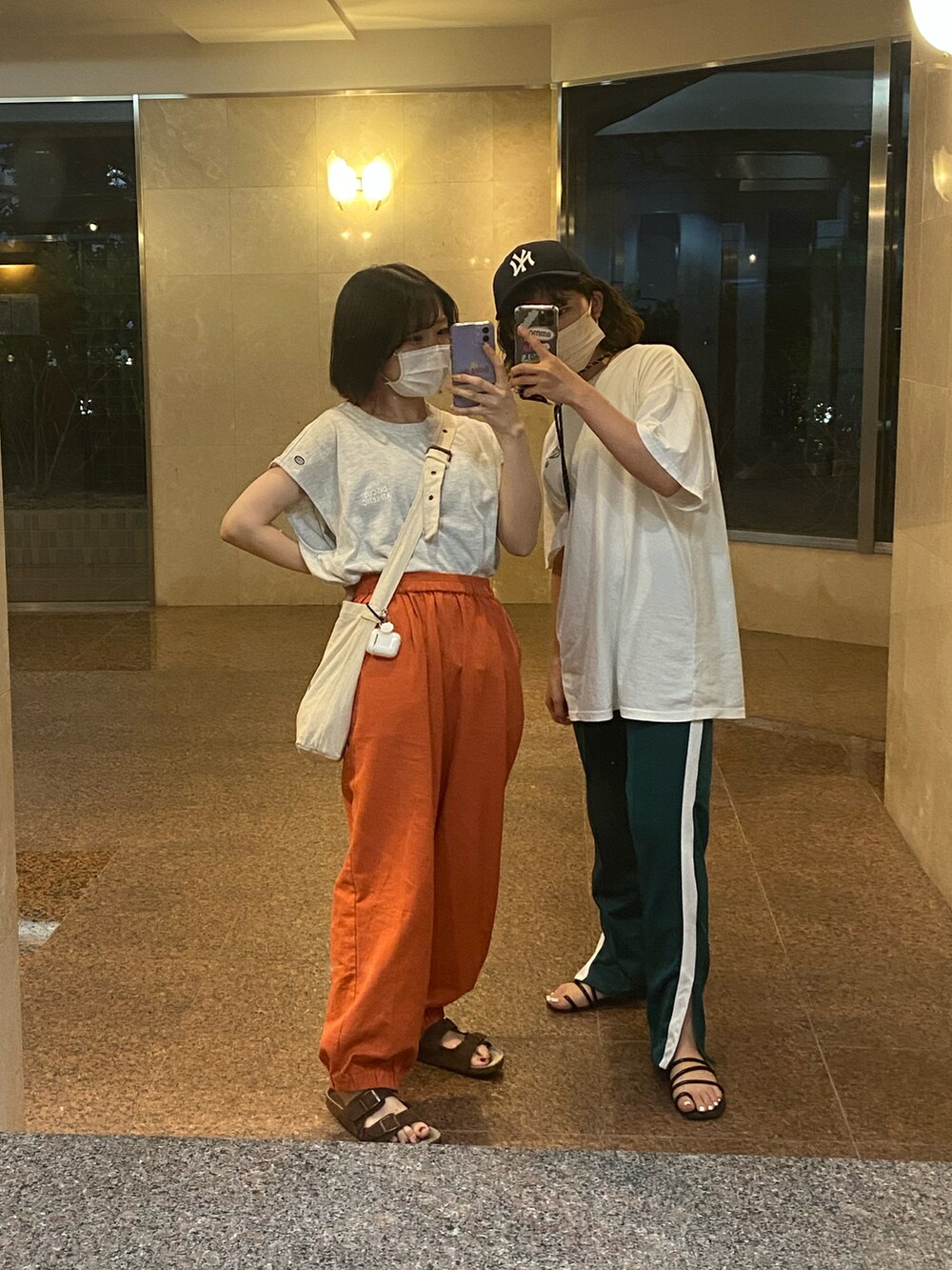 オレンジ系のその他パンツ、ブラウン系のサンダル、ホワイト系のショルダーバッグを着用したレディースの夏コーディネートの2枚目の写真