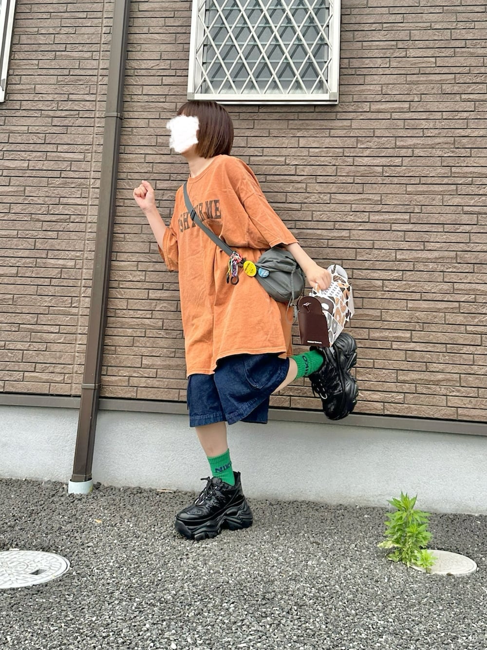 オレンジ系のTシャツ/カットソー、グリーン系のショルダーバッグ、ブルー系のカーゴパンツを着用したレディースの夏コーディネートの2枚目の写真