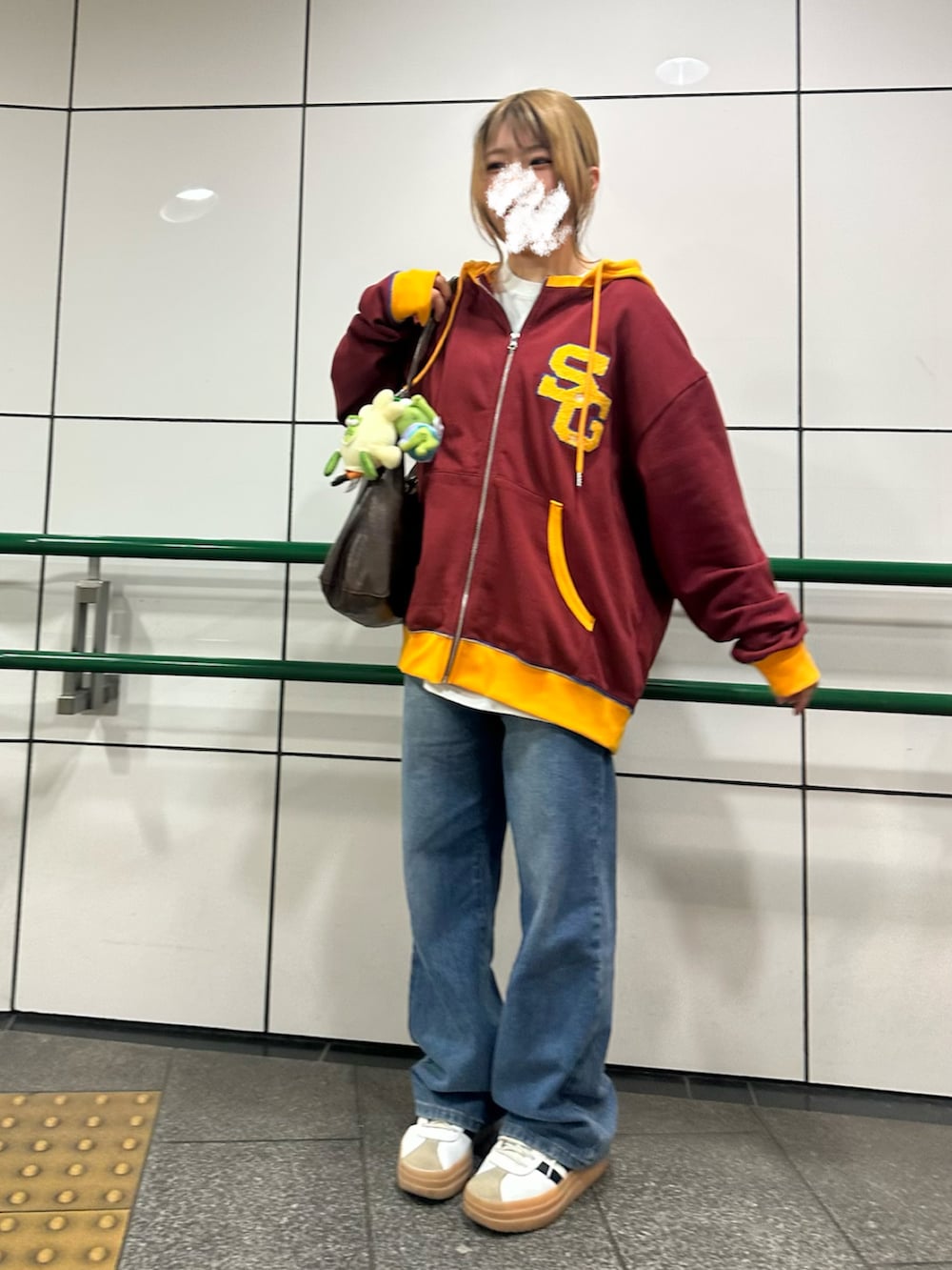 レッド系のパーカー、ブルー系のデニムパンツ、ホワイト系のスニーカーを着用したレディースの春コーディネートの2枚目の写真