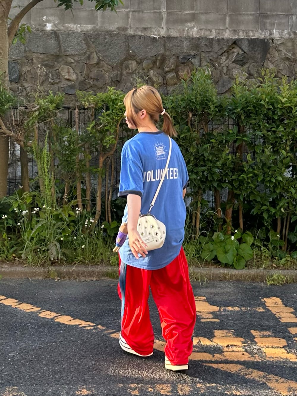 レッド系のスニーカー、ホワイト系のショルダーバッグ、ブルー系のTシャツ/カットソーを着用したレディースの春コーディネートの2枚目の写真