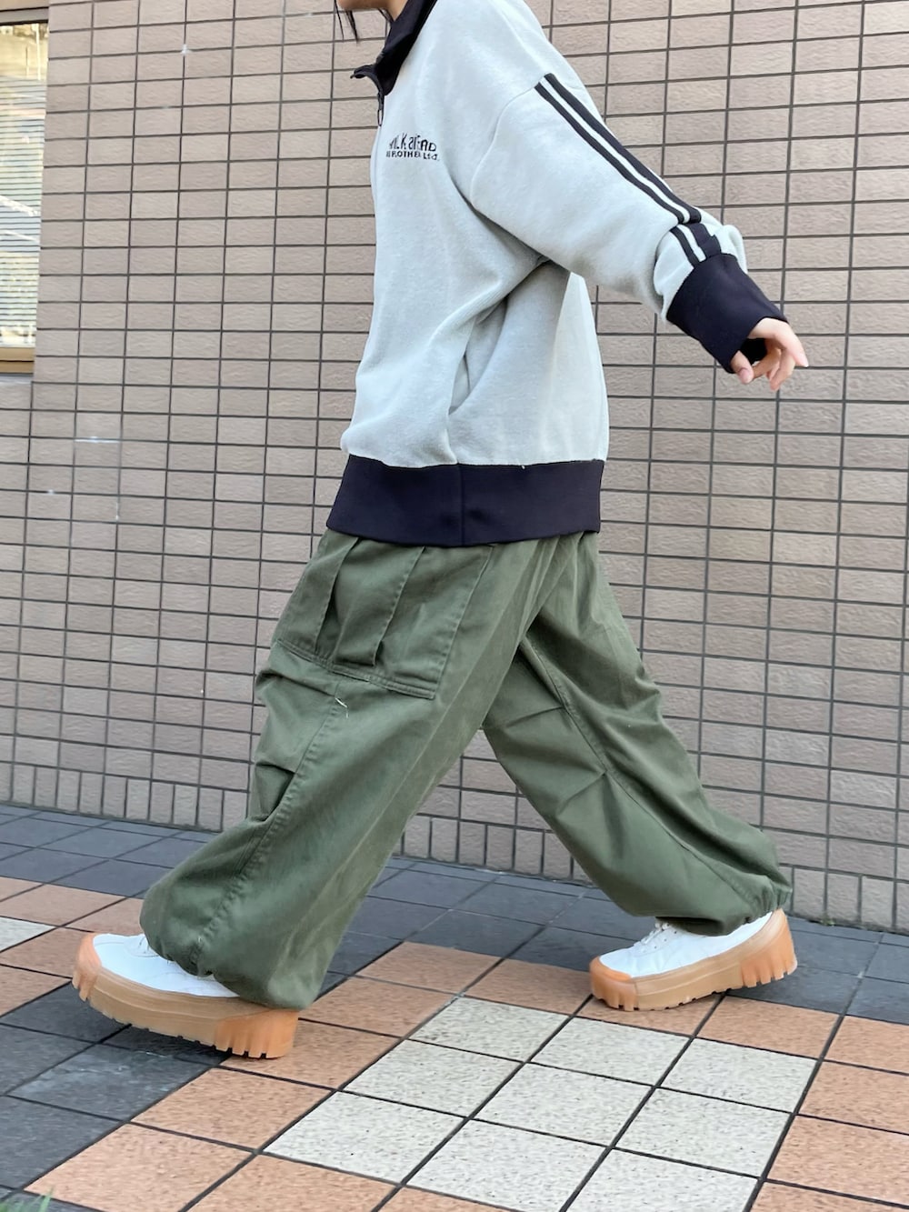 ホワイト系のスニーカー、グリーン系のパンツ、ブラウン系のショルダーバッグを着用したレディースの冬コーディネートの2枚目の写真