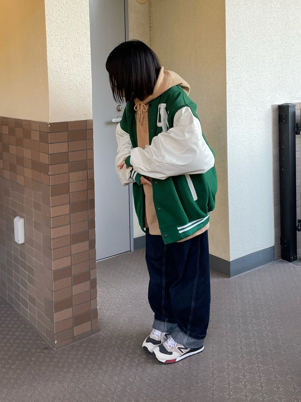 ブルー系のパンツ、ベージュ系のスニーカー、グリーン系のスタジャンを着用したレディースの秋コーディネートの2枚目の写真