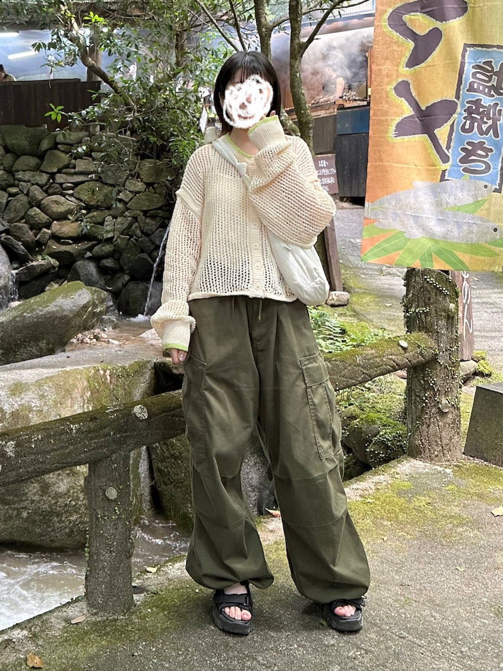 グリーン系のパンツ、ホワイト系のカーディガン/ボレロ、ホワイト系のキャミソールを着用したレディースの夏コーディネートの2枚目の写真