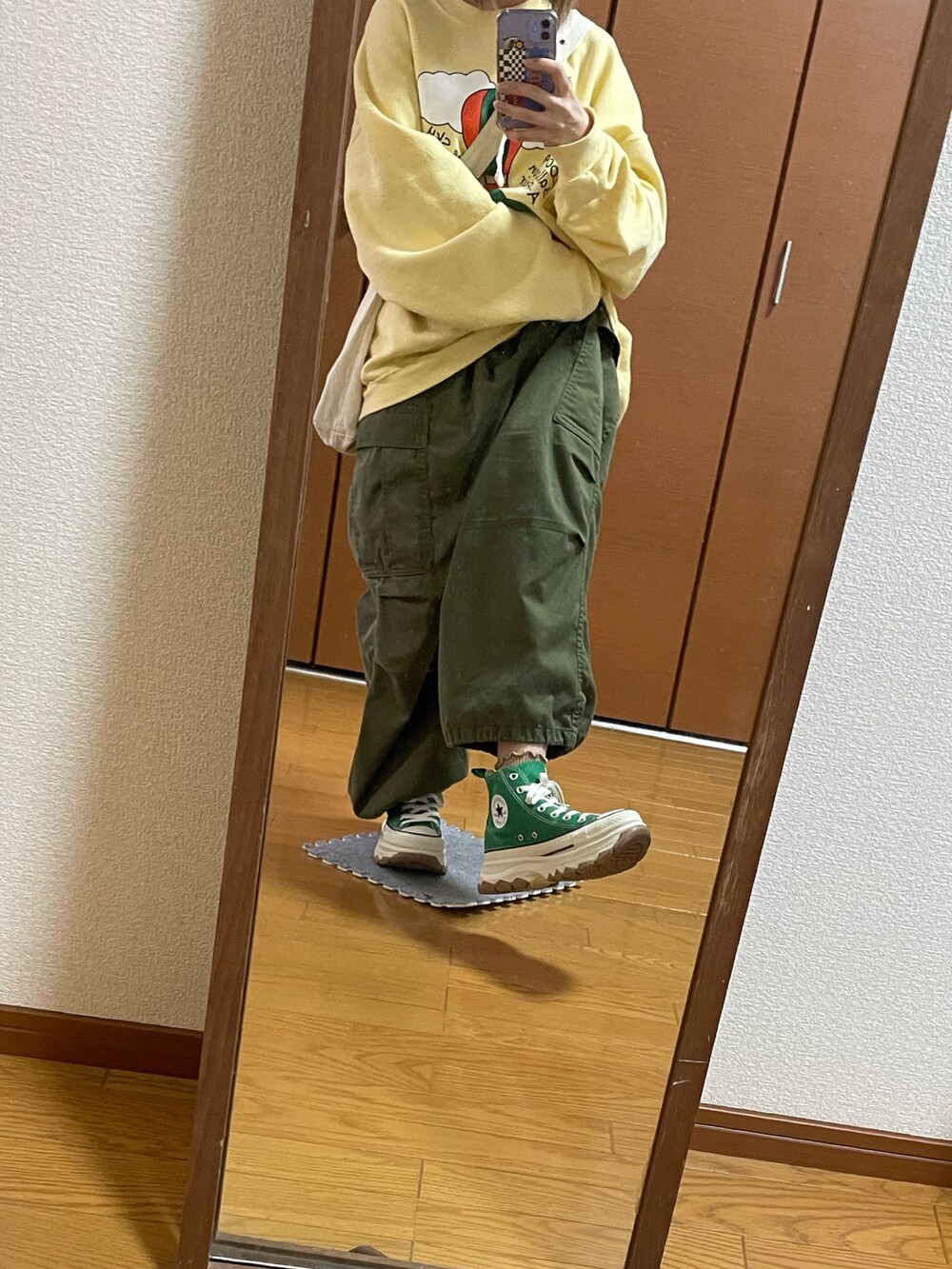 グリーン系のパンツ、イエロー系のスウェット、ホワイト系のショルダーバッグを着用したレディースの秋コーディネートの2枚目の写真