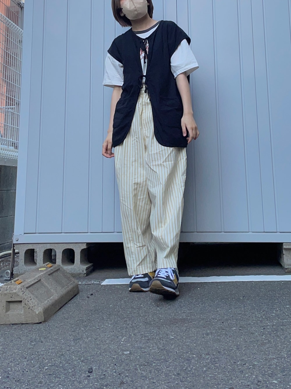 ブルー系のスニーカー、イエロー系のその他パンツ、ブラック系のベストを着用したレディースの夏コーディネートの2枚目の写真