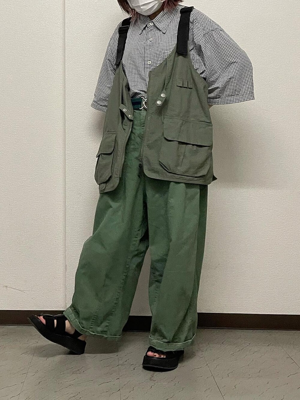 グリーン系のチノパンツ、ブラック系のサンダル、グリーン系のベストを着用したレディースの秋コーディネートの2枚目の写真