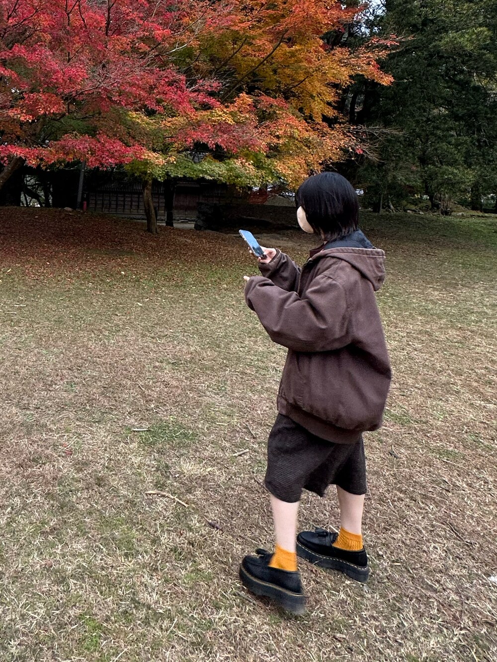 ブラウン系のブルゾン、オレンジ系のニット/セーター、ブラウン系のその他パンツを着用したレディースの冬コーディネートの2枚目の写真