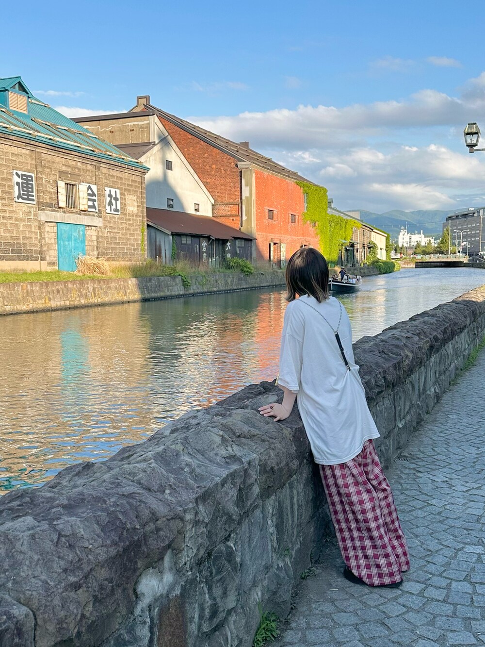 ホワイト系のTシャツ/カットソー、ブラック系のショルダーバッグ、レッド系のスラックスを着用したレディースの夏コーディネートの2枚目の写真