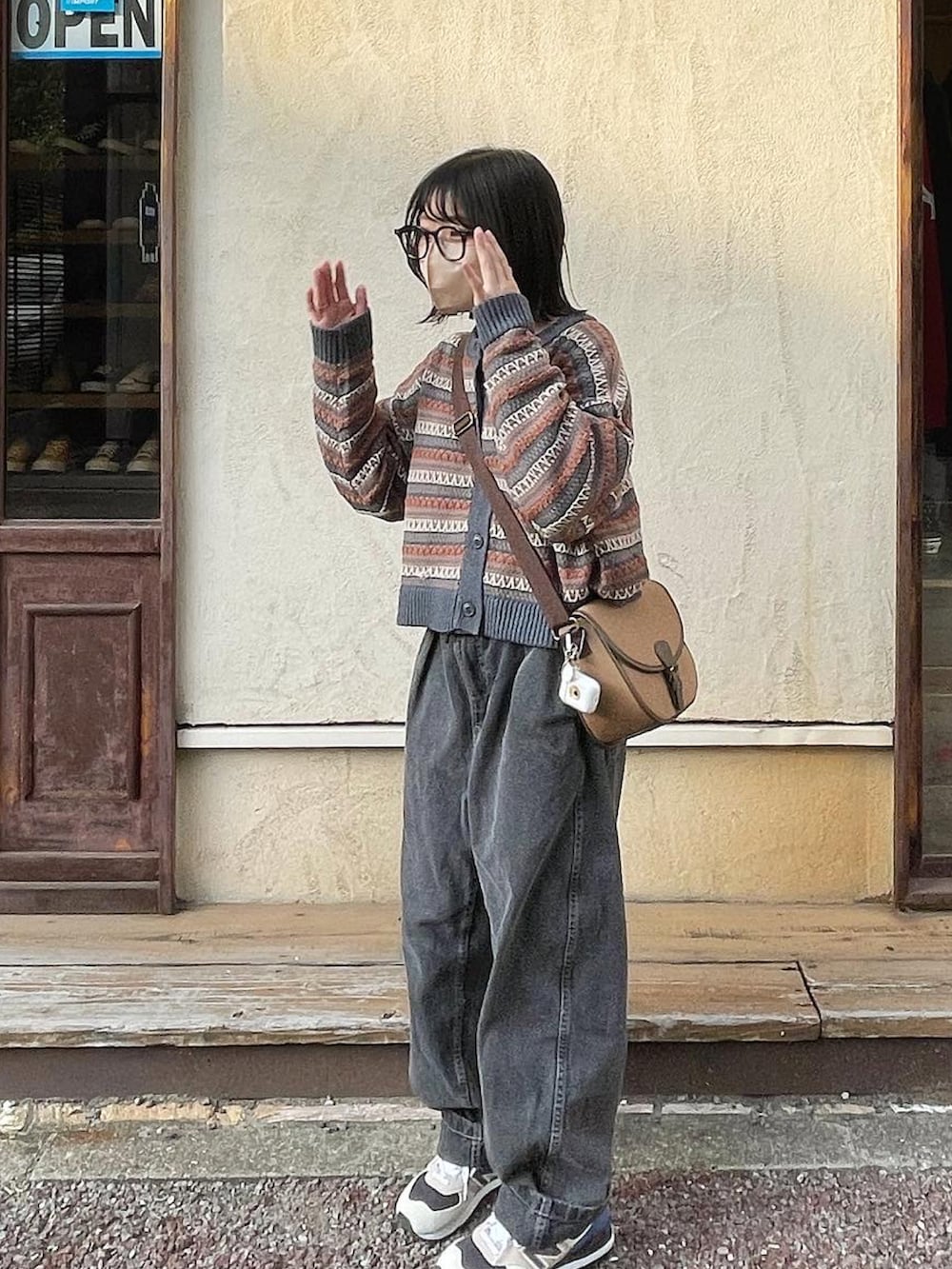 ブラック系のパンツ、ベージュ系のスニーカー、ブラウン系のショルダーバッグを着用したレディースの秋コーディネートの2枚目の写真