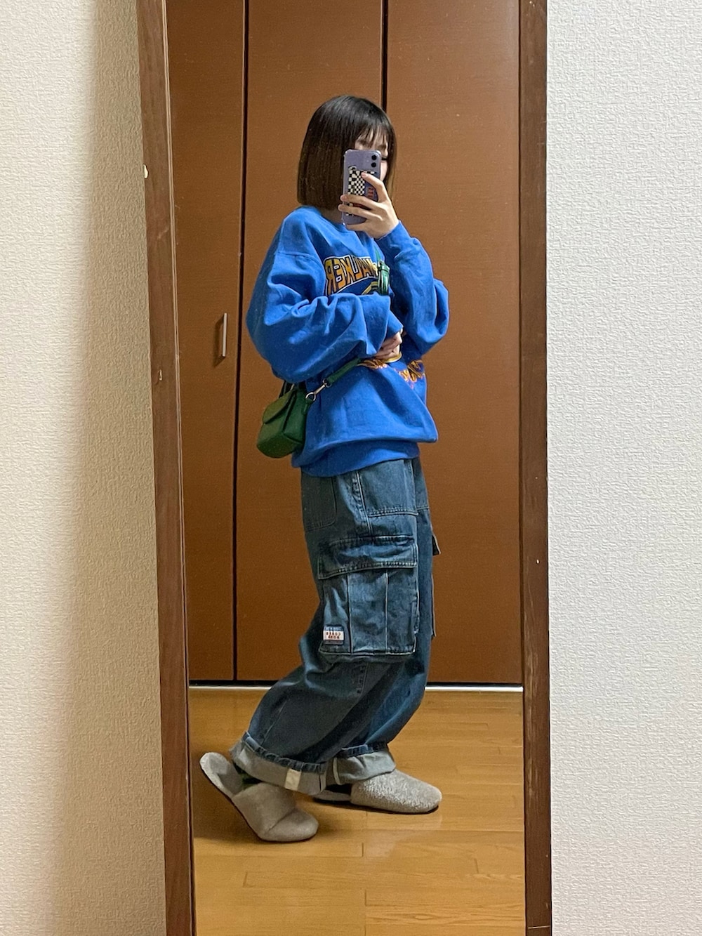 ブルー系のデニムパンツ、ブルー系のスウェット、グリーン系のショルダーバッグを着用したレディースの冬コーディネートの2枚目の写真