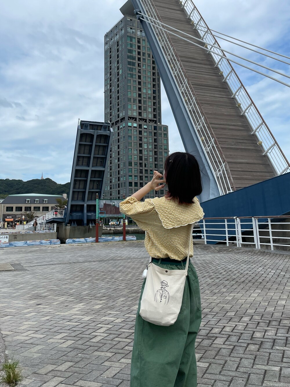 イエロー系のシャツ/ブラウス、ホワイト系のショルダーバッグ、グリーン系のチノパンツを着用したレディースの秋コーディネートの2枚目の写真