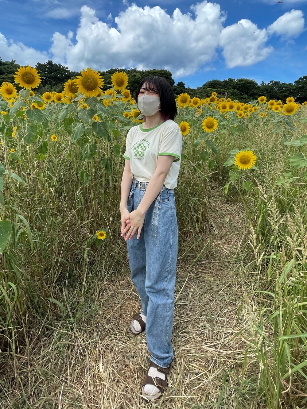 ブルー系のデニムパンツ、ホワイト系のTシャツ/カットソー、ブラウン系のサンダルを着用したレディースの夏コーディネートの2枚目の写真