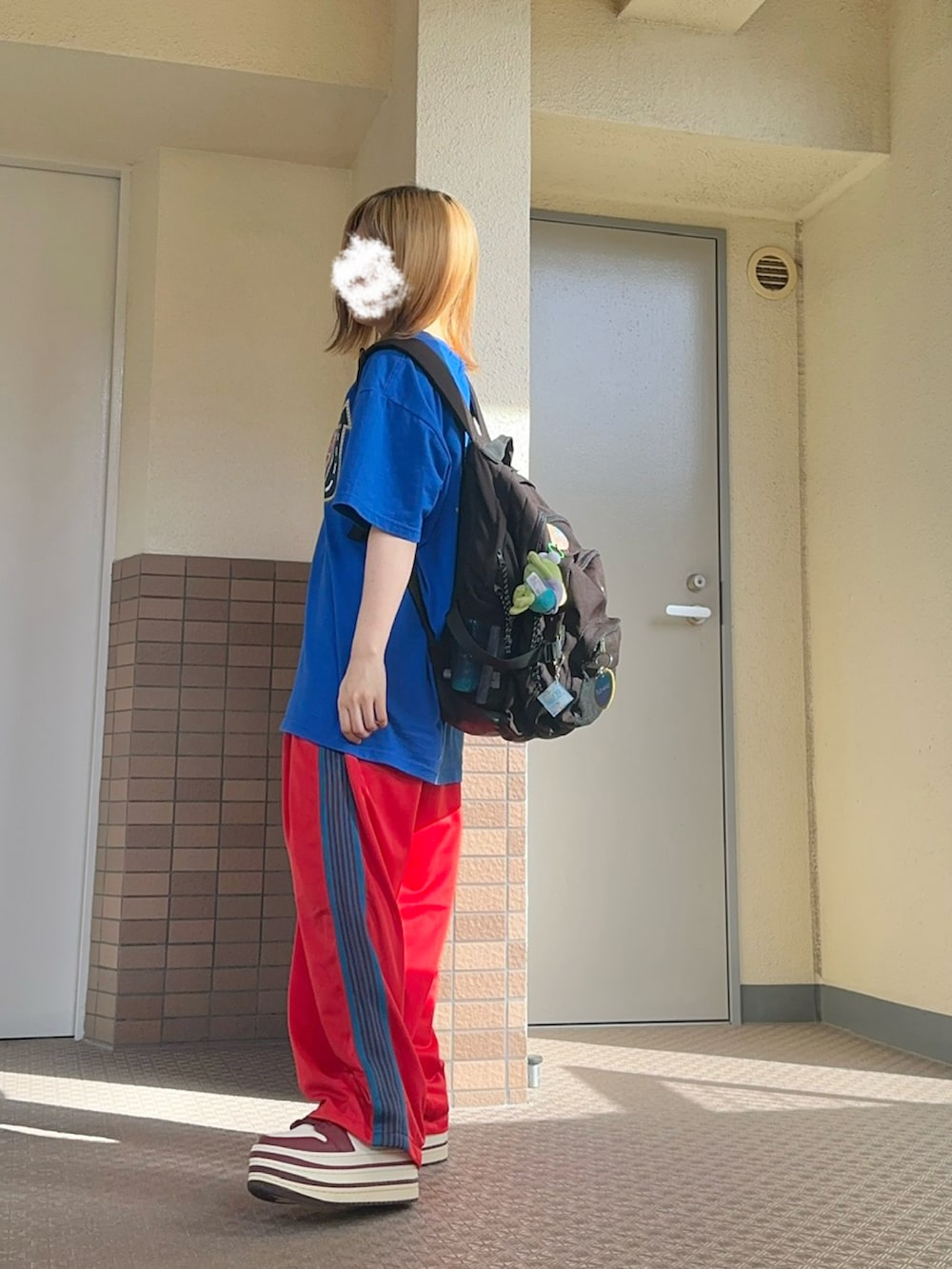 レッド系のスニーカー、ブラック系のバックパック/リュック、ブルー系のTシャツ/カットソーを着用したレディースの夏コーディネートの2枚目の写真