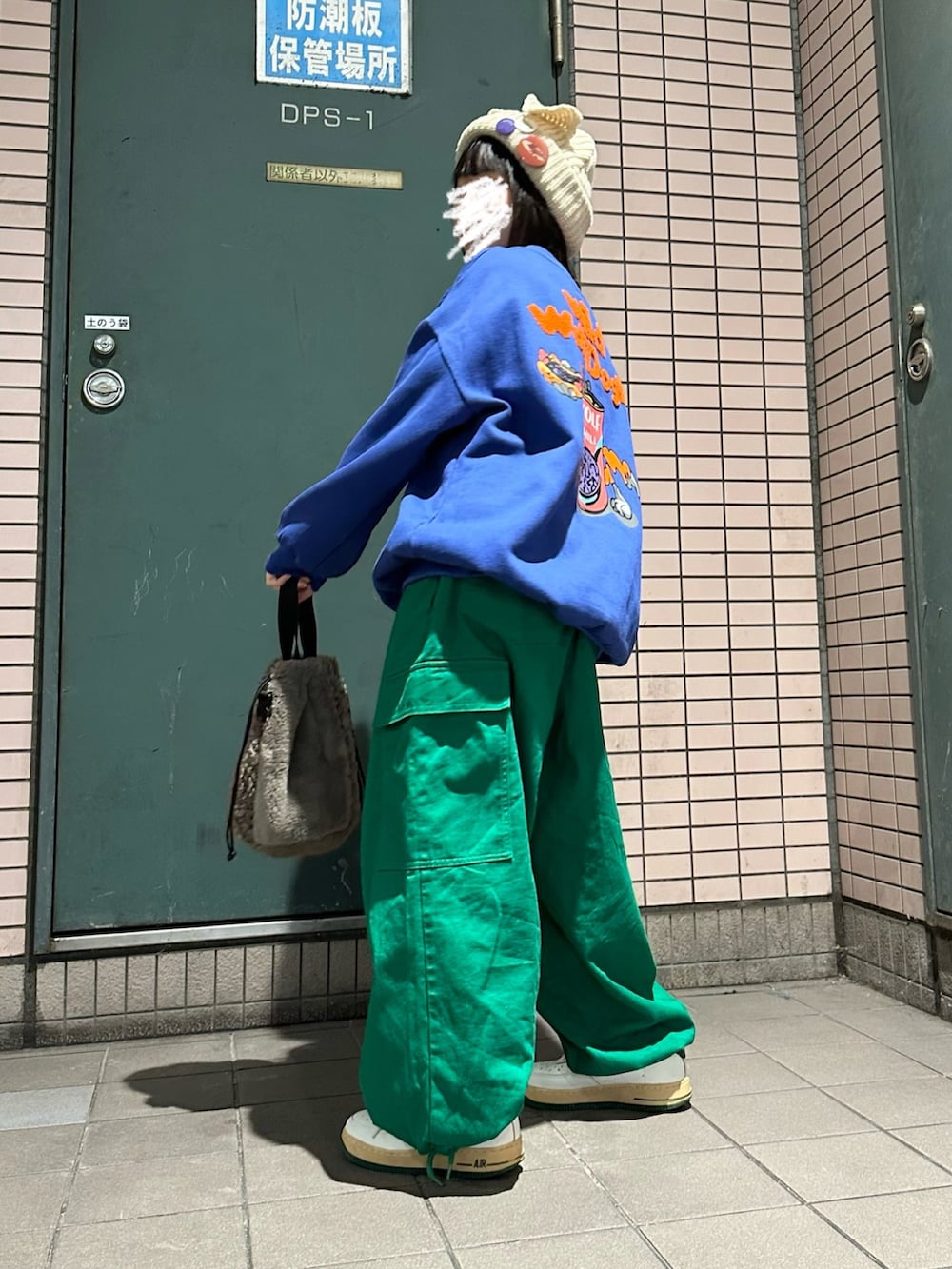 ベージュ系のスニーカー、グリーン系のチノパンツ、ブラウン系のショルダーバッグを着用したレディースの冬コーディネートの2枚目の写真