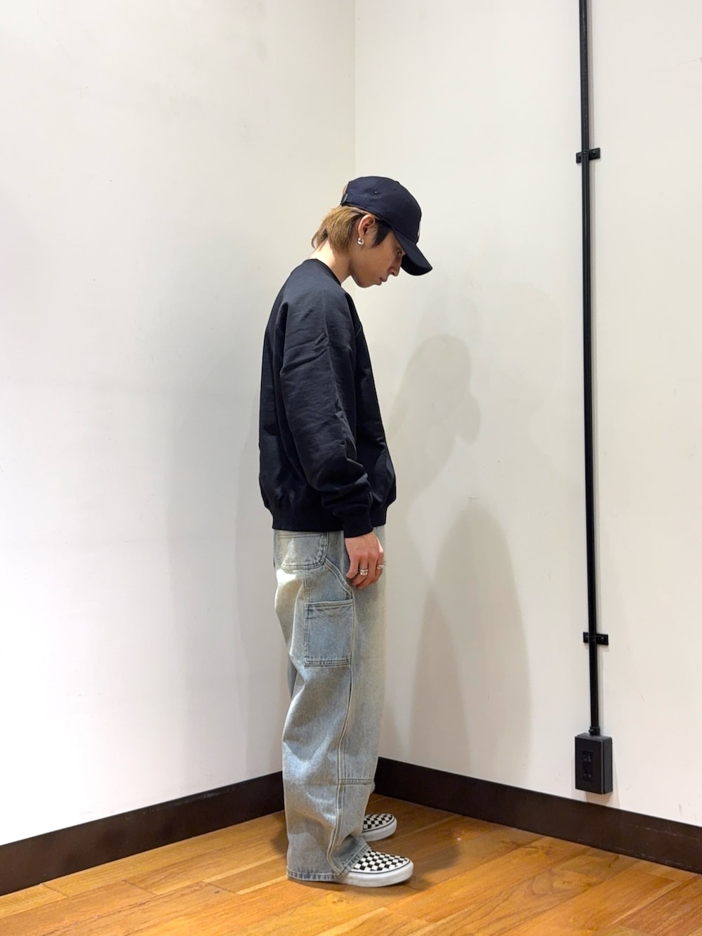 ブラック系のスウェット、ブルー系のデニムパンツ、ブルー系のキャップを着用したメンズの春コーディネートの4枚目の写真