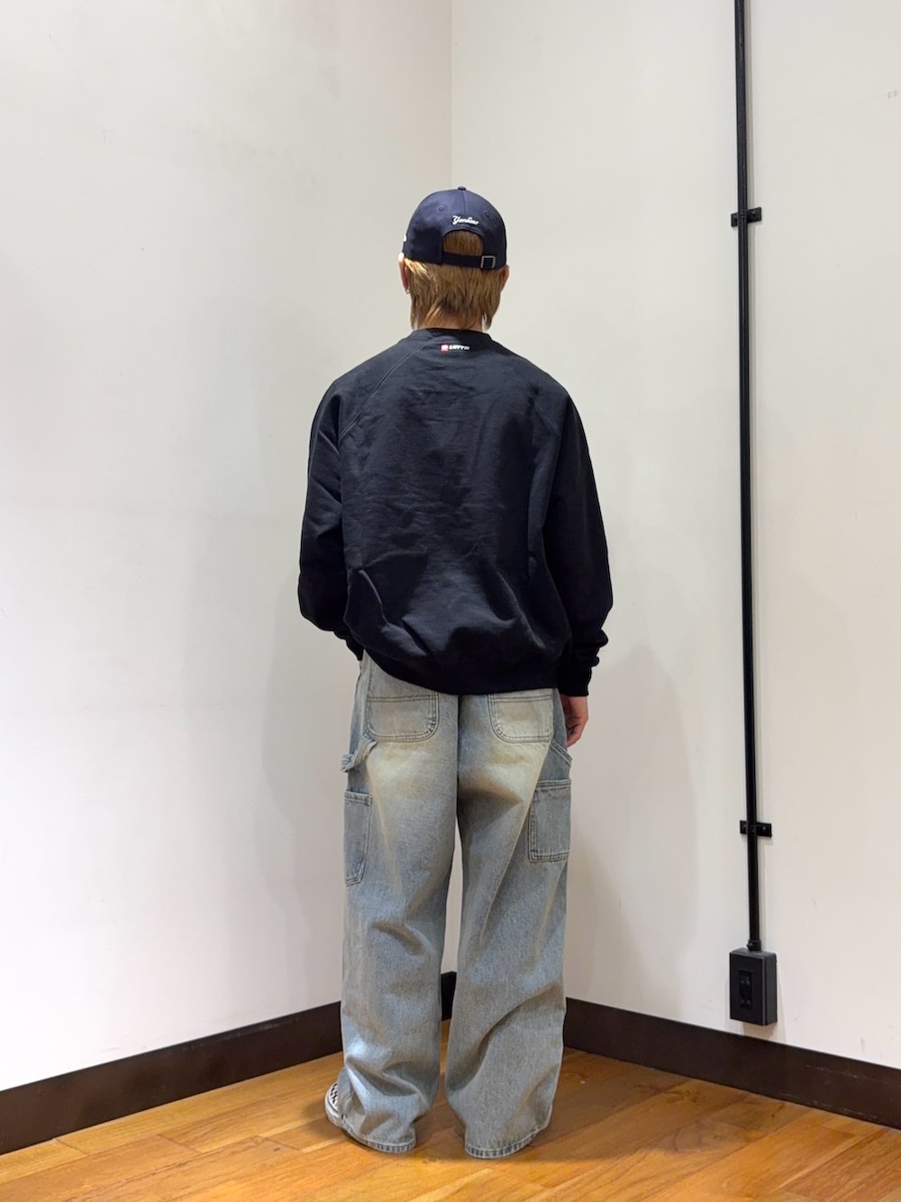 ブラック系のスウェット、ブルー系のデニムパンツ、ブルー系のキャップを着用したメンズの春コーディネートの3枚目の写真