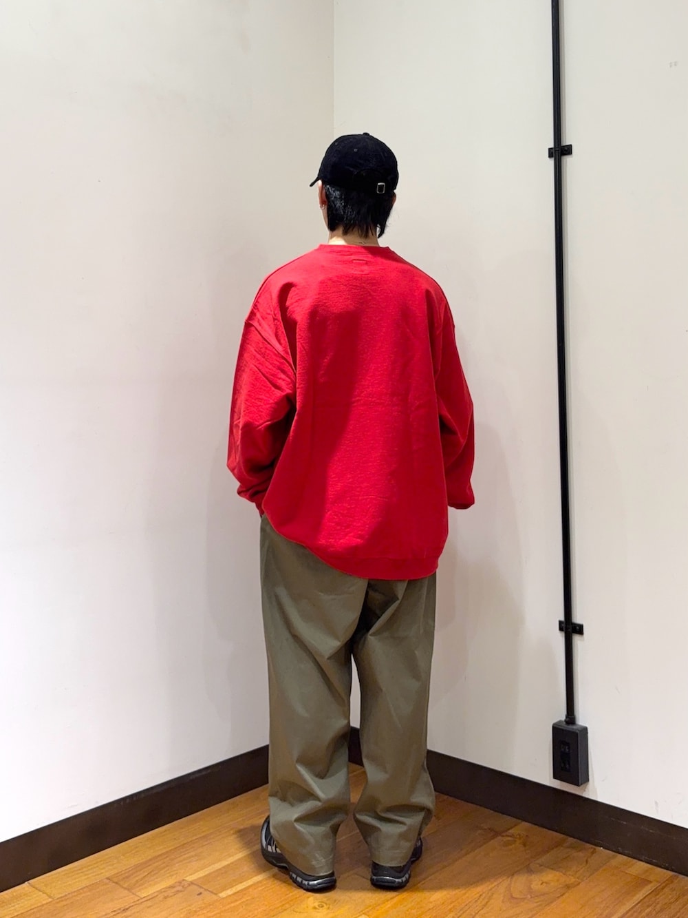 レッド系のスウェット、ブラウン系のその他パンツ、ブラック系のスニーカーを着用したメンズの秋コーディネートの3枚目の写真