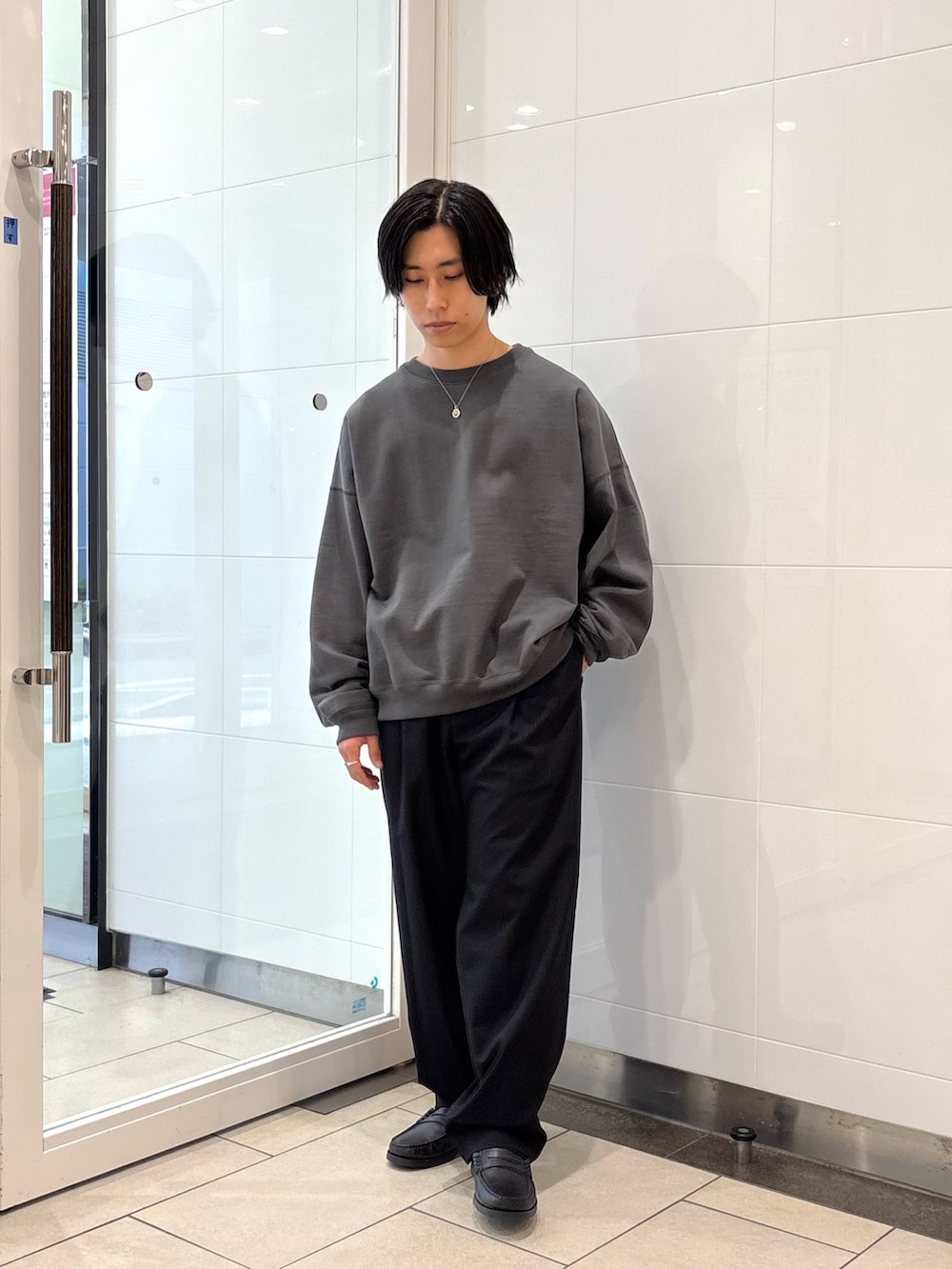 グレー系のスウェット、ブラック系のその他パンツ、ブラック系のローファーを着用したメンズの秋コーディネートの5枚目の写真