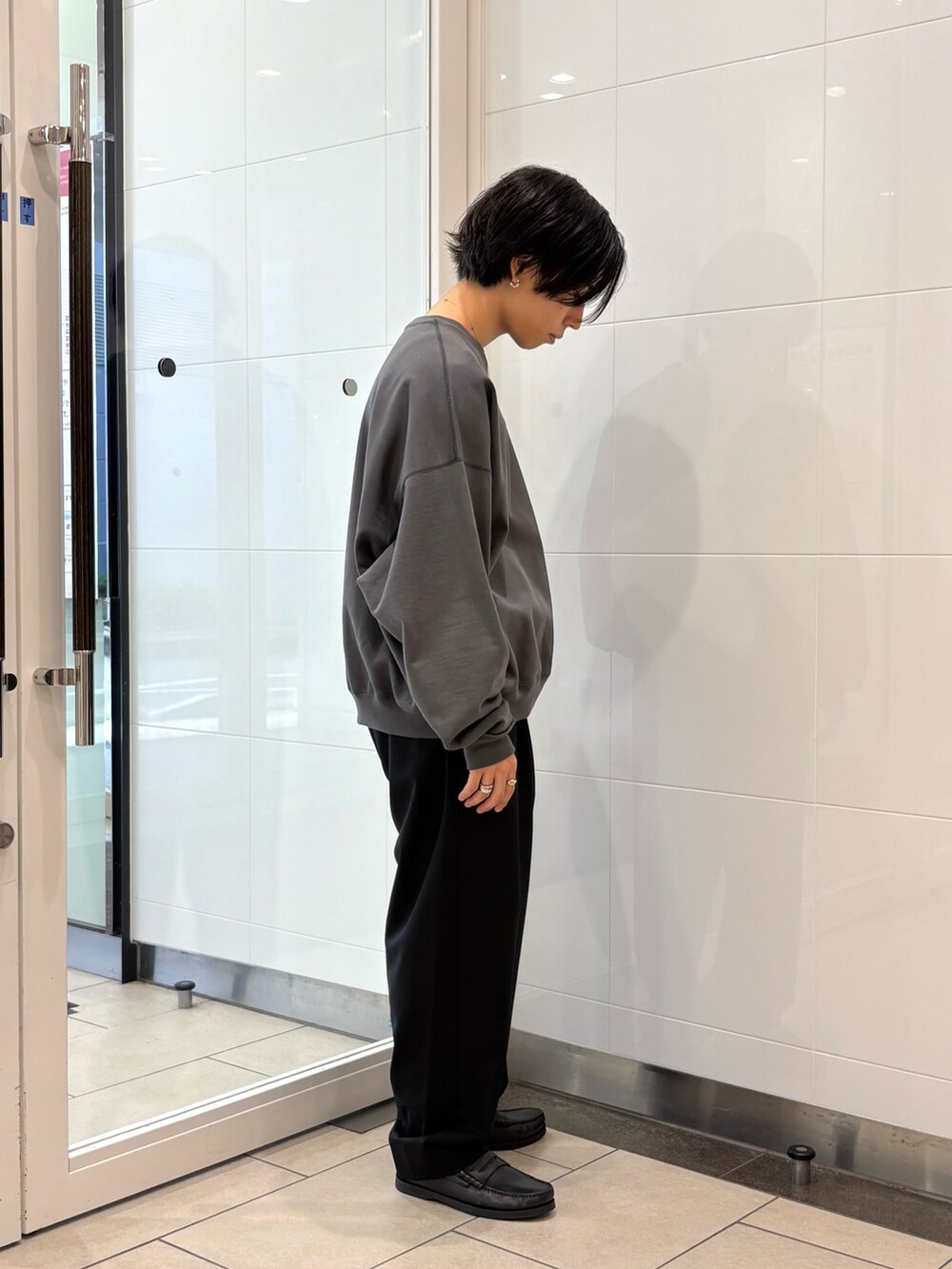 グレー系のスウェット、ブラック系のその他パンツ、ブラック系のローファーを着用したメンズの秋コーディネートの4枚目の写真