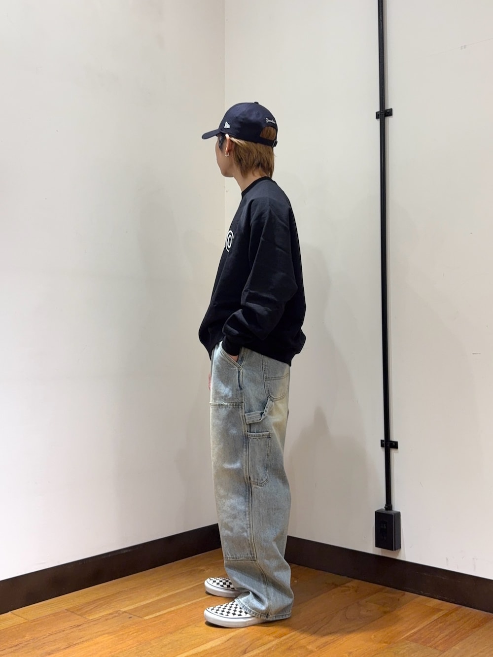 ブラック系のスウェット、ブルー系のデニムパンツ、ブルー系のキャップを着用したメンズの春コーディネートの2枚目の写真