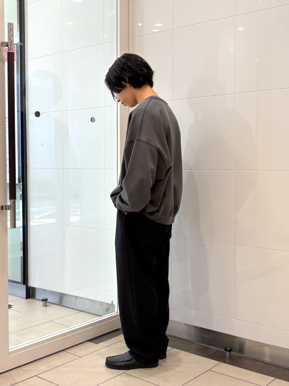 グレー系のスウェット、ブラック系のその他パンツ、ブラック系のローファーを着用したメンズの秋コーディネートの2枚目の写真