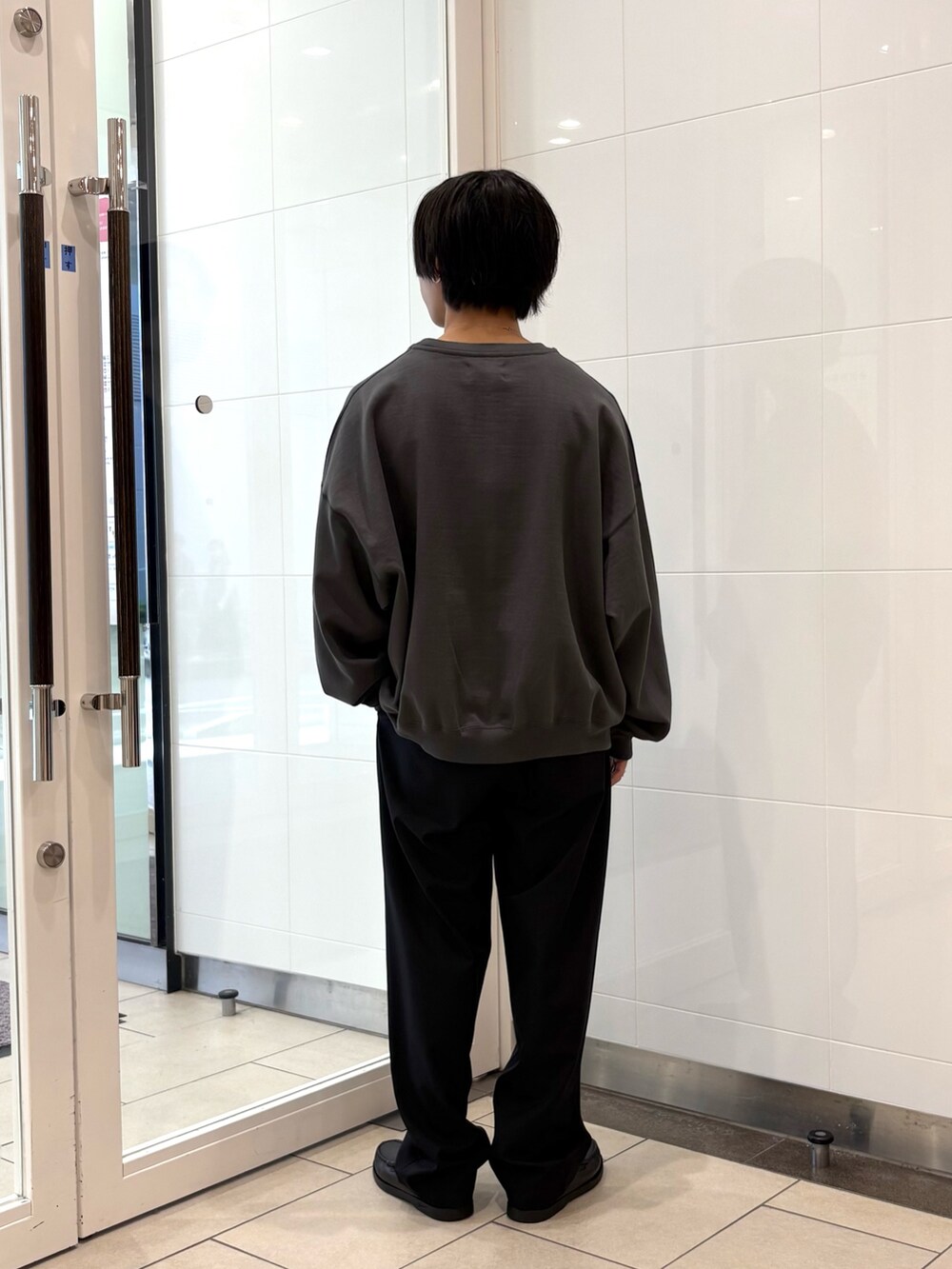 グレー系のスウェット、ブラック系のその他パンツ、ブラック系のローファーを着用したメンズの秋コーディネートの3枚目の写真