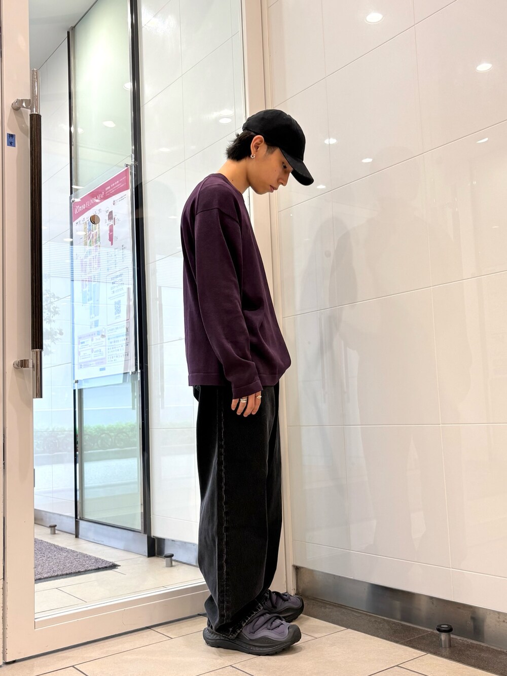 パープル系のニット/セーター、ブラック系のデニムパンツ、ブラック系のスニーカーを着用したメンズの秋コーディネートの4枚目の写真