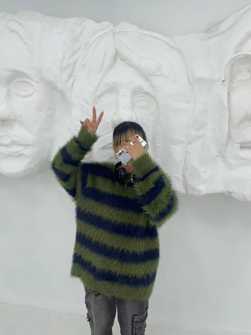 グリーン系のニット/セーター、ブラック系のカーゴパンツ、ブラック系のスニーカーを着用したレディースの冬コーディネートの3枚目の写真