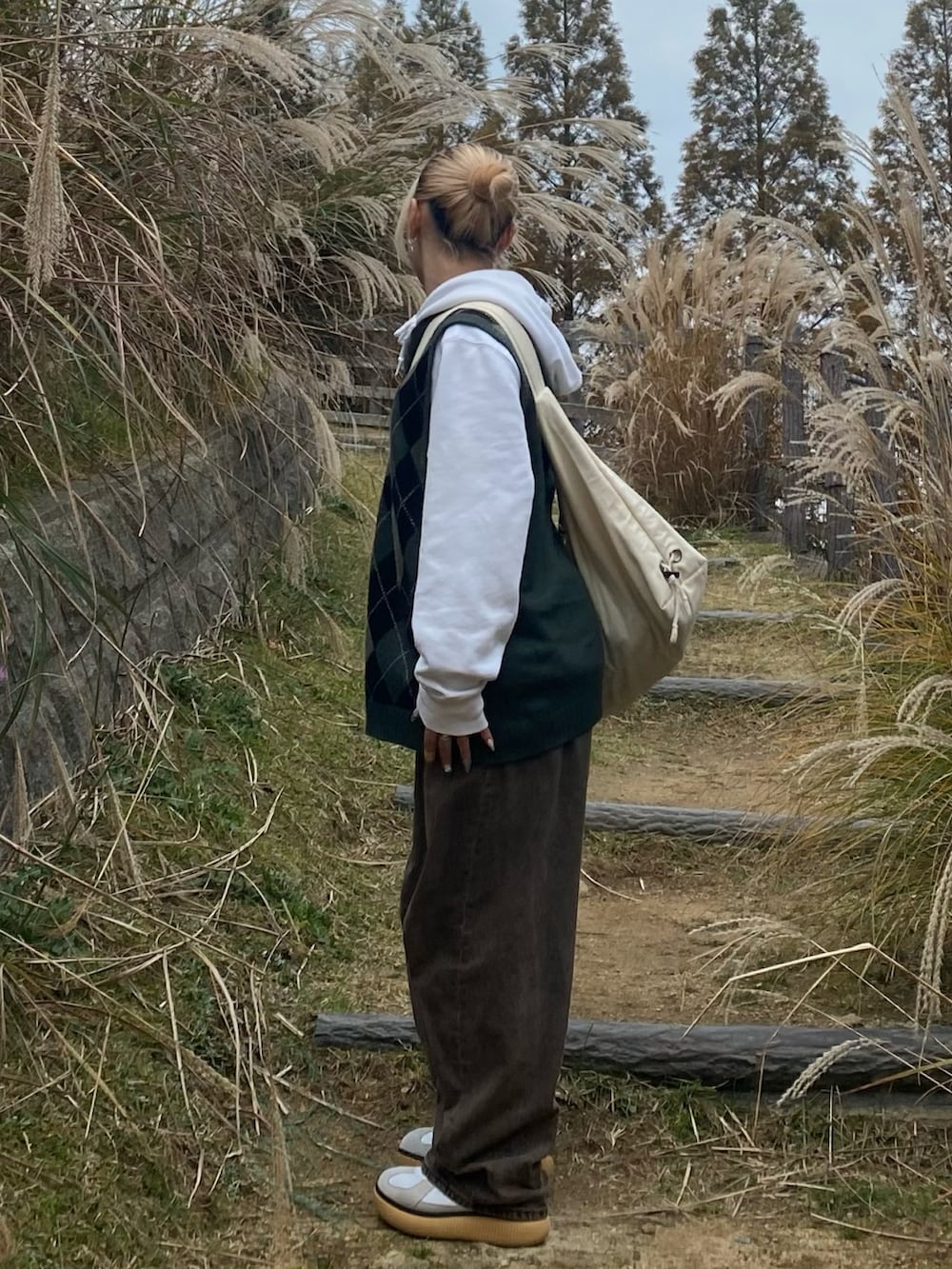 ホワイト系のパーカー、グリーン系のニット/セーター、ブラウン系のデニムパンツを着用したレディースの冬コーディネートの2枚目の写真