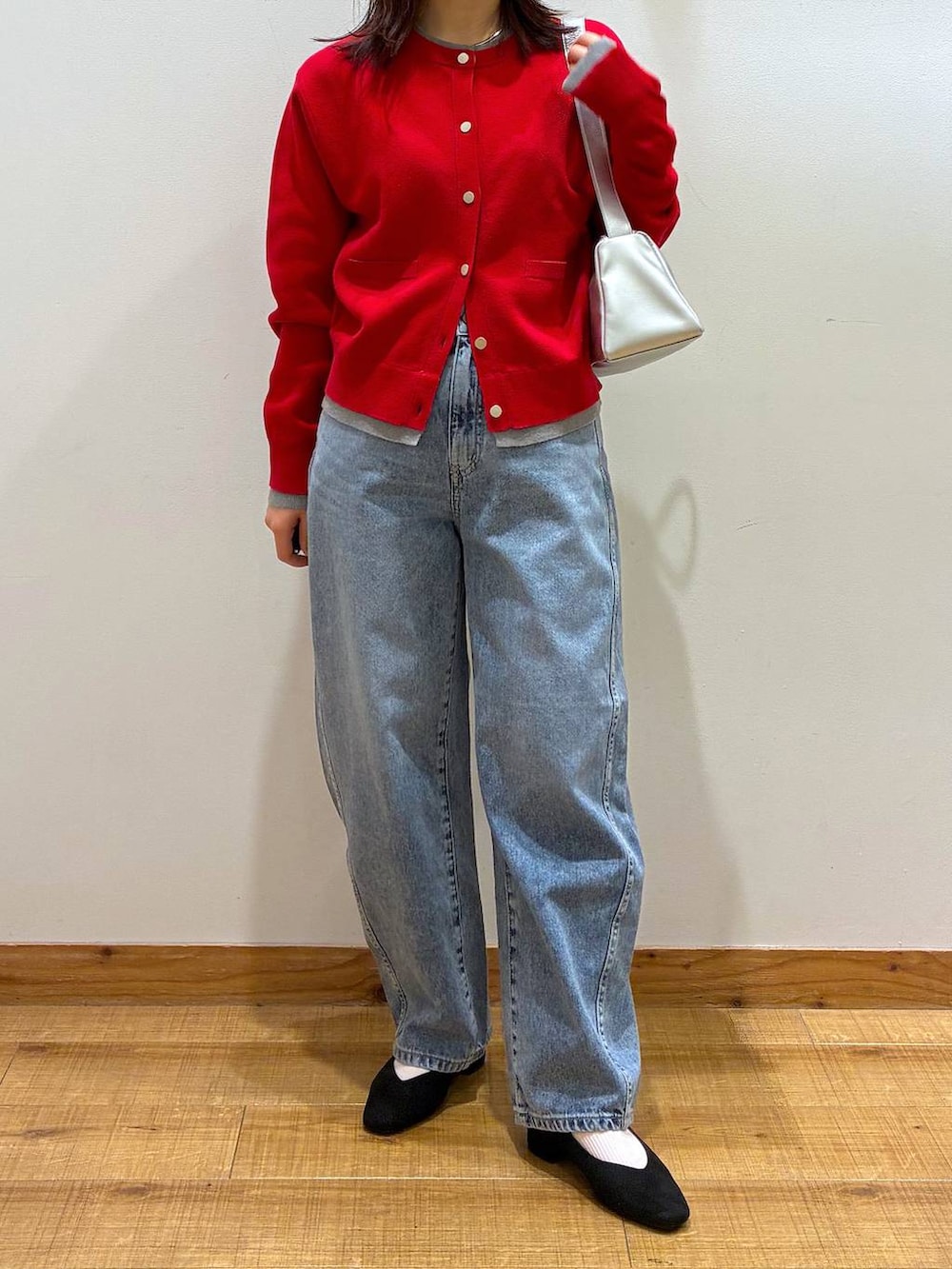 ブラック系のパンプス、ブルー系のデニムパンツ、ホワイト系のトートバッグを着用したレディースの春コーディネートの4枚目の写真