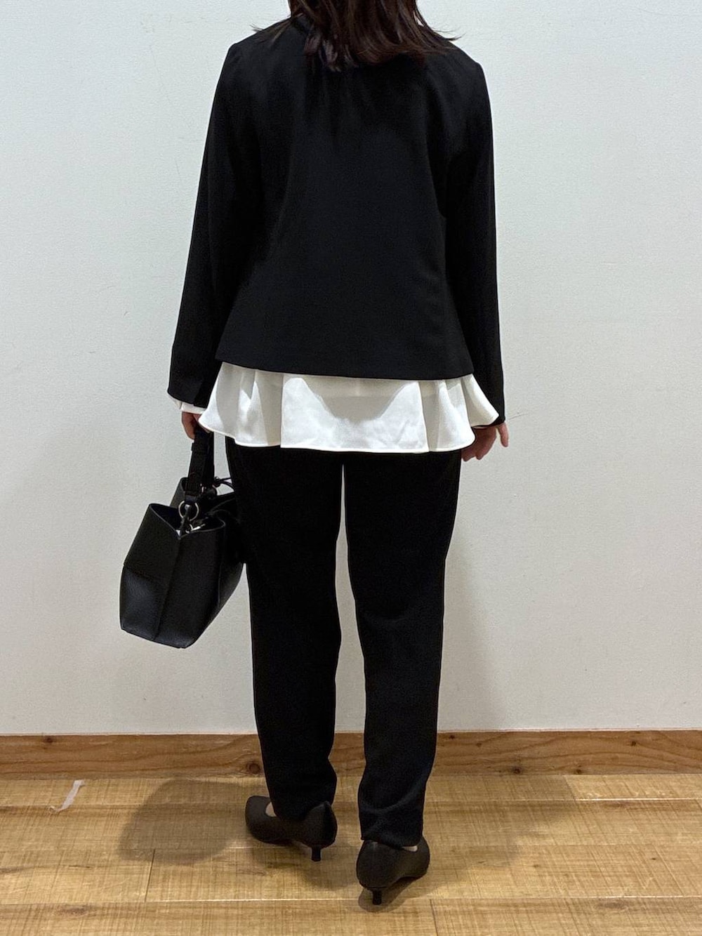 ブラック系のパンプス、ブラック系のセットアップ、ブラック系のショルダーバッグを着用したレディースの冬コーディネートの3枚目の写真