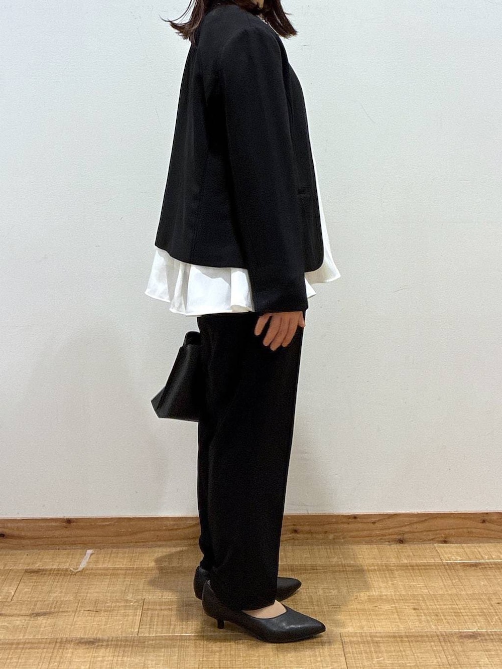 ブラック系のパンプス、ブラック系のセットアップ、ブラック系のショルダーバッグを着用したレディースの冬コーディネートの2枚目の写真