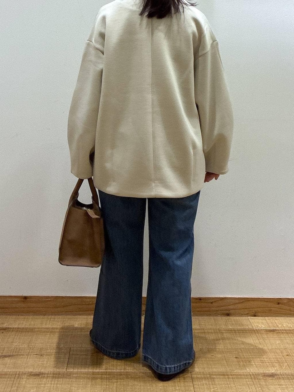 ブラック系のバレエシューズ、ブルー系のデニムパンツ、ベージュ系のショルダーバッグを着用したレディースの冬コーディネートの3枚目の写真