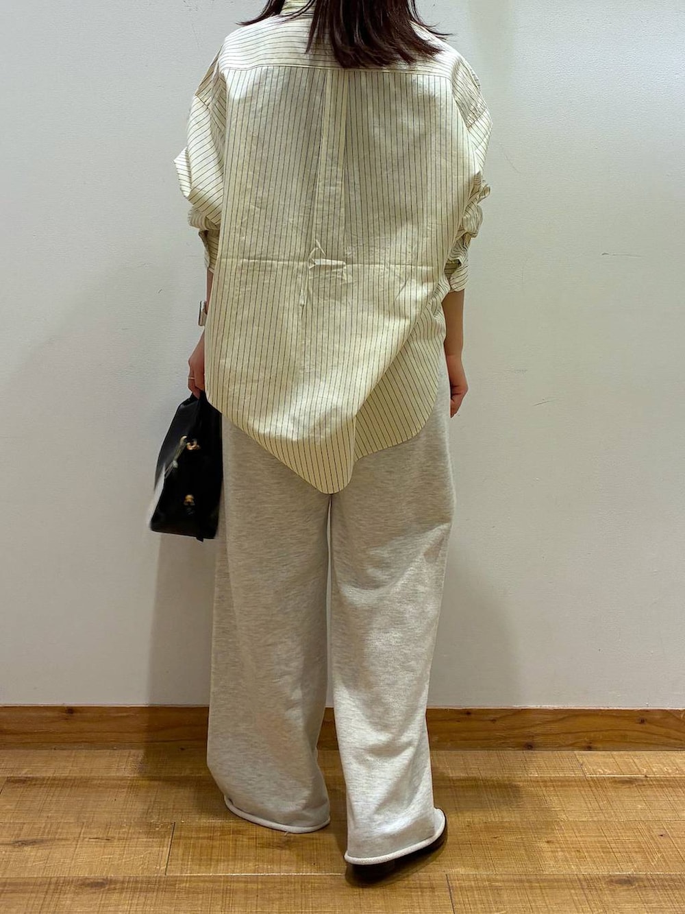 ブラック系のショルダーバッグ、ブラック系のパンプス、ホワイト系のスウェットパンツを着用したレディースの春コーディネートの2枚目の写真