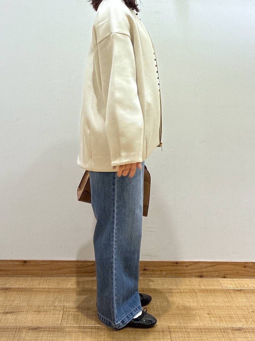 ブラック系のバレエシューズ、ブルー系のデニムパンツ、ベージュ系のショルダーバッグを着用したレディースの冬コーディネートの2枚目の写真